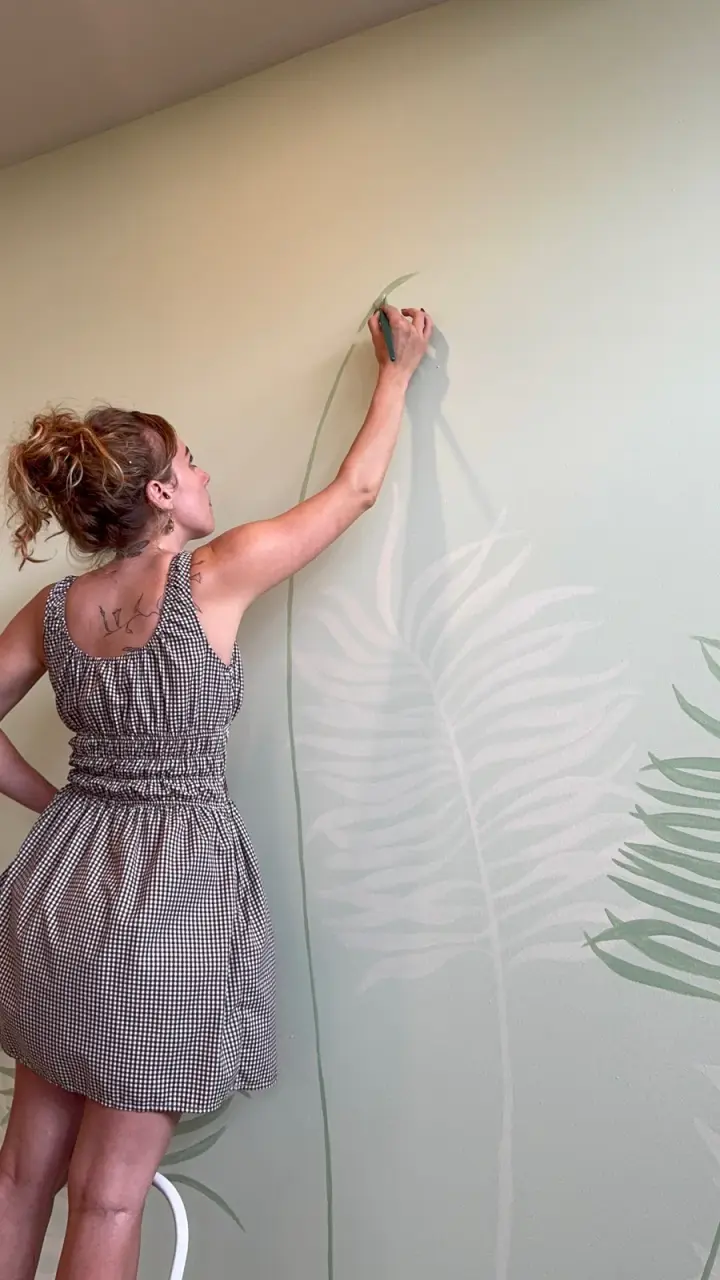 Shannon Hope McAnney hand painting a botanical interior mural