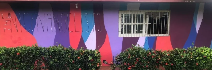 Wide exterior wall mural painted with bold overlapping fields of red blue teal and purple